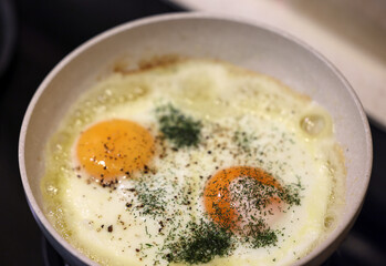 Frying pan with fried egg sprinkled with dill
