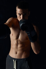 sports guy on a black background in boxing gloves inflated torso cropped view 