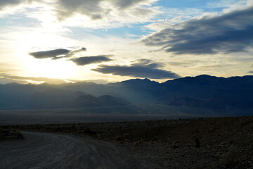 Fototapeta na wymiar evening sky with the sun breaking through clouds with a view to the panamint range and the Death Valley Wash in the National Park