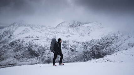 A hiker with a large backpack in snow covered mountains
