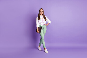 Fototapeta na wymiar Full length photo of girl hold pc hand hip look camera wear trousers footwear white shirt isolated violet color background