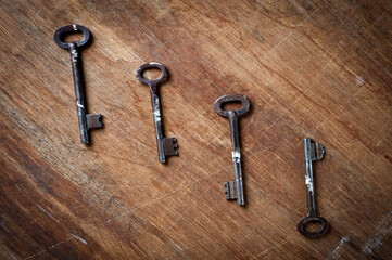 Old iron door keys lying on an old wooden surface.