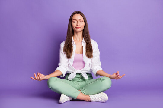 Photo portrait full body view of girl sitting in lotus pose meditating isolated on vivid purple colored background