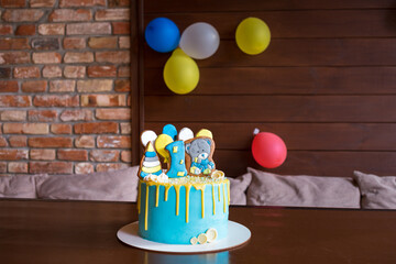 Blue cake for the boy's first birthday with gingerbread in the form of a bear.