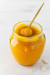 Pumpkin puree in a glass jar with a spoon.