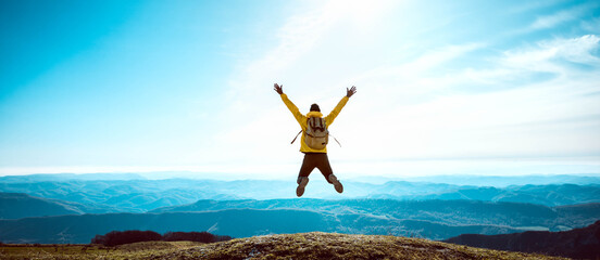 Happy man with open arms jumping on the top of mountain - Hiker with backpack celebrating success...