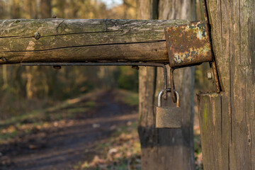 Padlock on a wooden gate with a footpath into the forest in the background, seen at Saarner Mark, Muelheim an der Ruhr, North Rhine-Westphalia, Germany