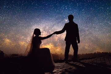 silhouette Romantic wedding couple  holding hand on grass hill in milky way with  stars  field...