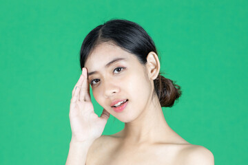 Beauty young Asian woman touching her face over green isolated background. Healthy skin care concept.