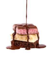 Mix of porous chocolate pieces and chocolate syrup, isolated on white background. Black, white and pink aerated chocolate.
