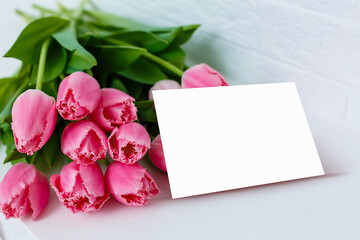 Pink tulip bouquet, gift box and balnk paper on blue wooden background, copy space