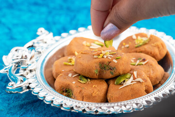 Indian Mithai Brown Mathura Peda Or Meetha Pera Made Of Condensed Milk Fudge Khoya Mawa Kesar Khoa Pista Mava Malai In Pure Desi Ghee Being Decorated With Dry Fruits By Hands Of Girl During Festival