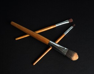 three wooden make-up brushes on a dark base