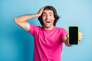 Photo of excited brunet hair guy showing cellphone for sale hand head empty space isolated on blue color background