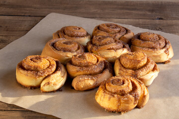 Freshly baked cinnamon buns with spices and cocoa filling on parchment paper. Sweet Homemade Pastry christmas baking. Close-up. Kanelbule - swedish dessert.