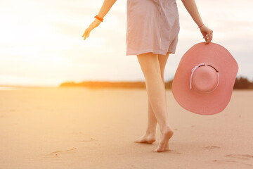 close-up of female feet walking along the sandy beach to meet the sunrise. a young woman in a short...