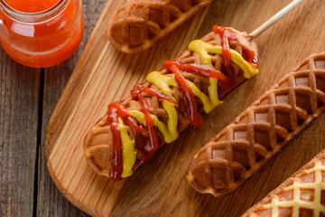 Appetizing corn dogs covered with ketchup and mustard