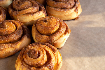 Freshly baked cinnamon buns with spices and cocoa filling on parchment paper. Sweet Homemade Pastry christmas baking. Close-up. Kanelbule - swedish dessert.