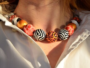 Safari print Beaded Necklace with animal skin print on a young woman's neck. Hand painted multicolored beads wooden jewelry	
