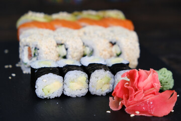 Set of Sushi Rolls with tuna, salmon, cucumber, avocado on a black table. close-up, shallow depth of field.