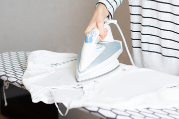 Woman is ironing clothes. The girl holds an iron on an ironing board.