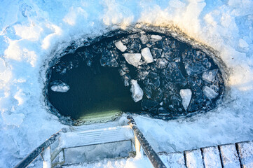 Fototapeta na wymiar ladder down into hole in ice on lake
