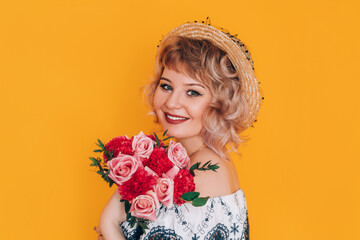 A woman in a dress holding a beautiful bouquet of flowers in front of a yellow background. Holiday gift.