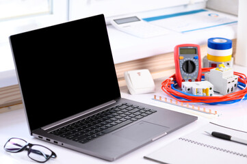 . Electrical installation courses. On the table there is a computer, cable, tester, automatic switch. Online learning