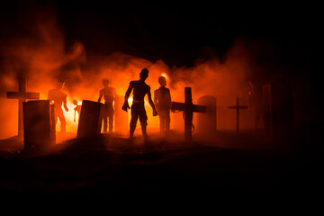 Obraz na płótnie Canvas Scary view of zombies at cemetery dead tree, moon, church and spooky cloudy sky with fog, Horror Halloween concept with glowing pumpkin. Selective focus