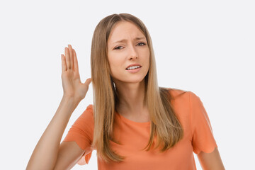 A hard of hearing young beautiful woman putting her hand to ear and listens. The concept of...