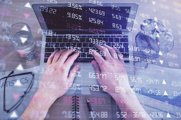 Multi exposure of man's hands typing over computer keyboard and forex graph hologram drawing. Top...