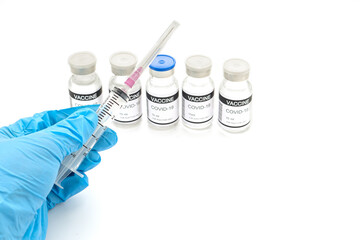 Hand holding a syringe with Covid-19 vaccine bottles placed on a white background. Vaccine for prevention, immunization, and treatment from coronavirus infection. Space for text