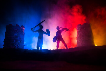 Medieval battle scene. Silhouettes of figures as separate objects, fight between warriors at night. Creative artwork decoration. Foggy background.