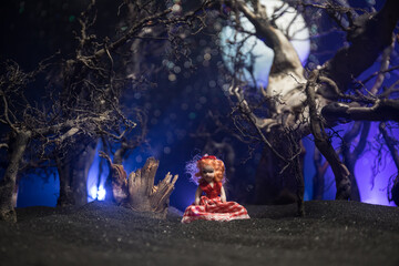 Horror Halloween decorated conceptual image. Alone girl with the light in the forest at night....