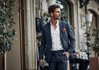 Handsome male model in checked suit walking on the street - obrazy, fototapety, plakaty