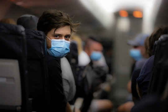 Man wearing medical face mask inside airplane during flight to protect against coronavirus. new normal concept, covid 19 and virus personal protection, mandatory masks,