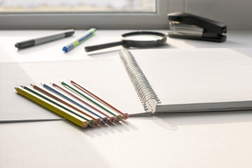 Pencils of different colors lie on an open drawing notebook. Copy space.