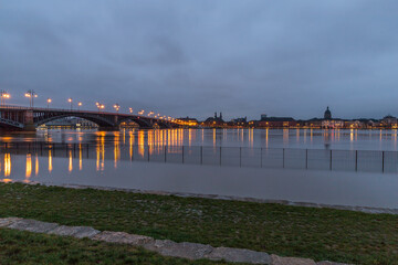 Beleuchtete Brücke über den Rhein bei Mainz an einem Winterabend mit Hochwasser