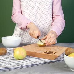 
Close-up of woman cutting pear on cutting board at kitchen table at home