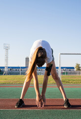 Young woman doing stretching at the stadium