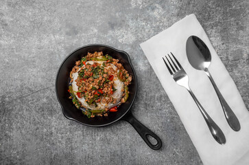 Top view Rice topped with stir-fried minced pork and basil in mini black pan., Popular Thai street food.