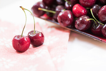 Cherries on wooden table with napkin and water drops macro background