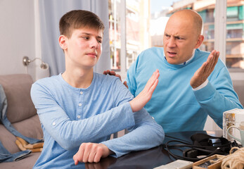 Teenage boy making stop gesture with his hand to scolding father