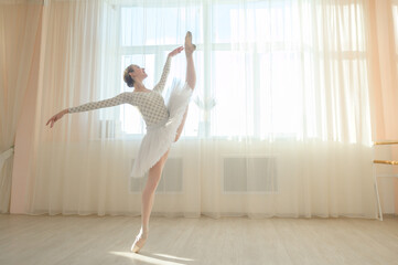 Beautiful ballerina in body and white tutu is training in a dance class. Young flexible dancer...