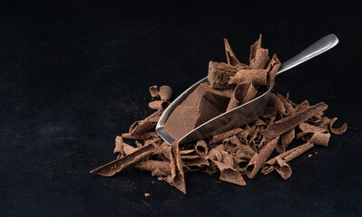 chocolate with grated nuts in a spoon on a black table