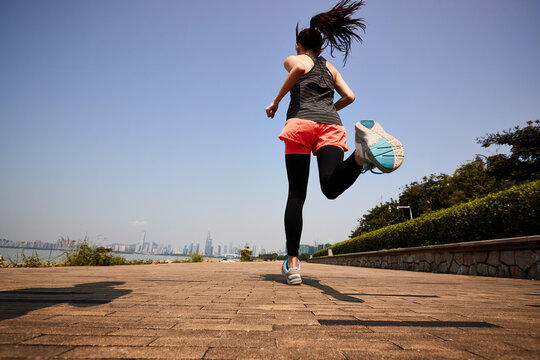 young asian woman running outdoors in seaside city park