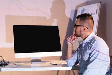 Fototapeta na wymiar businessman in glasses looking at computer monitor with blank screen