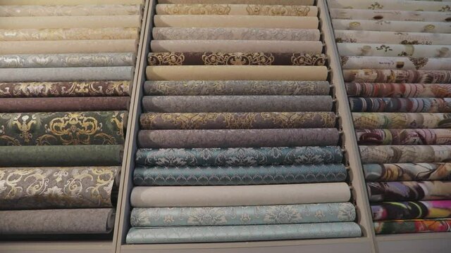 Sample in the store. Stands with rolls of wallpaper samples in the store. Stands with new samples. Rolls with wallpaper. Closeup