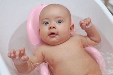 Beautiful baby girl bathes in the bathroom