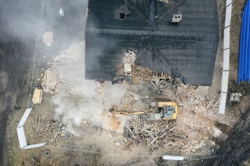 Yellow excavator destroys building. Heavy duty machine is demolishing a brick building. Demolition...